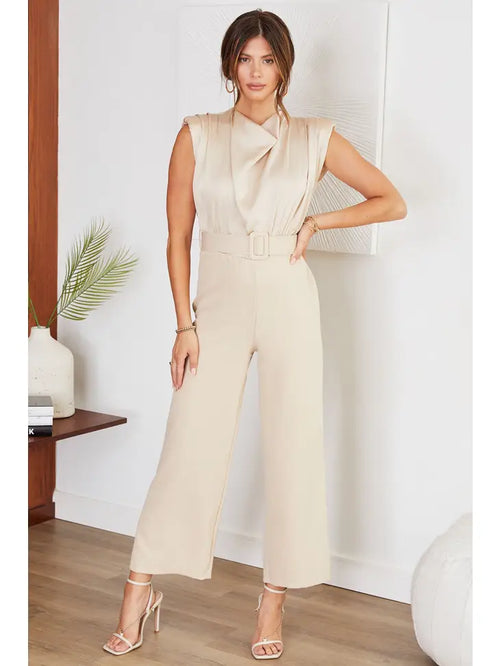 A nude colored jumpsuit with a cowl neckline and a capri length with a flared hemline.